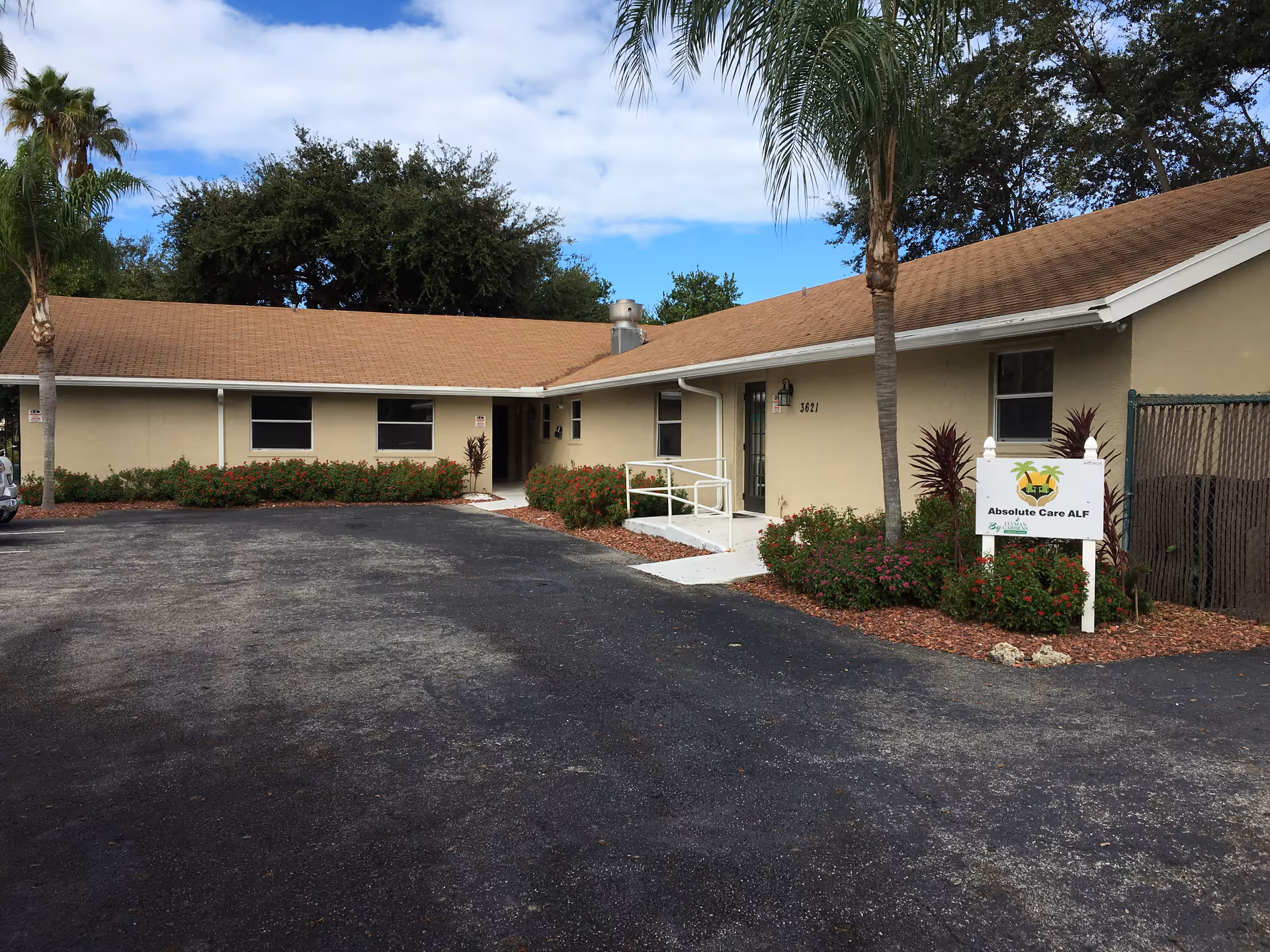 Single-story beige care facility exterior with parking lot, palm trees, and Absolute Care ALF sign.