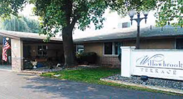 Exterior view of Willowbrook Terrace senior living facility with sign and entry.