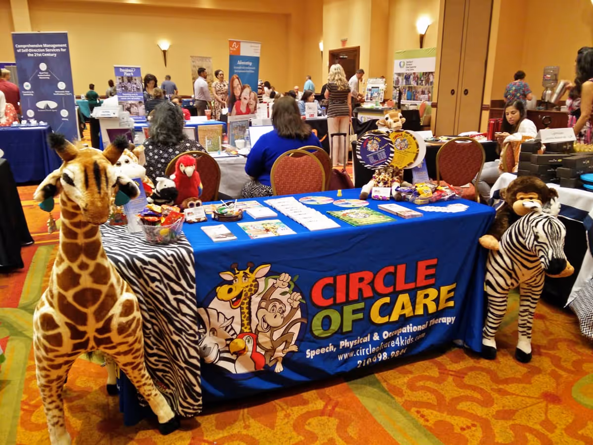 Circle of Care booth at a convention with banners, tables, and attendees.