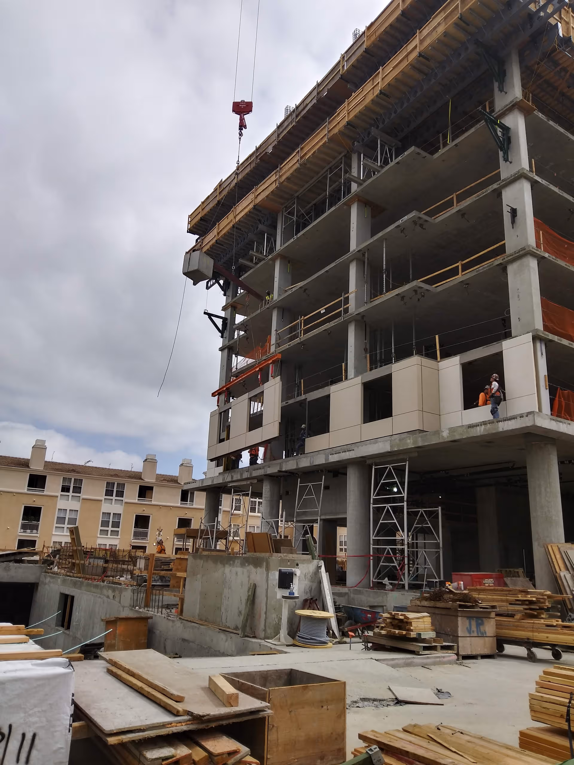 A partially built multi-story building with scaffolding, a crane, and workers on-site.