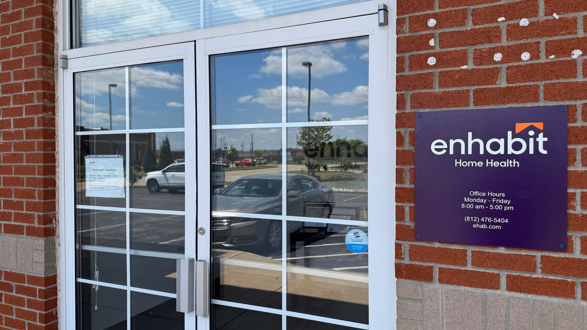 Brick building exterior with glass doors and an Enhabit sign.