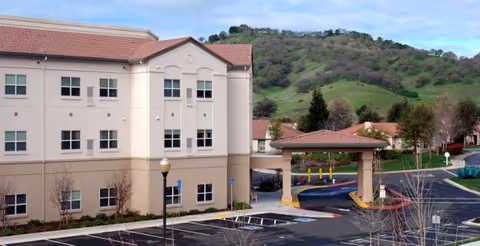 Exterior view of Quail Creek at Paradise Valley building with driveway and hillside backdrop.