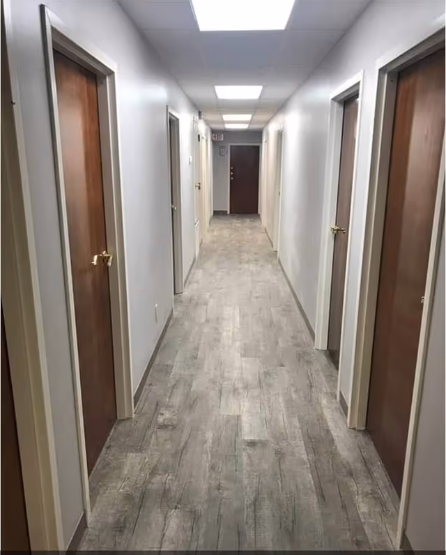 Long, empty hallway with closed wooden doors along both sides.