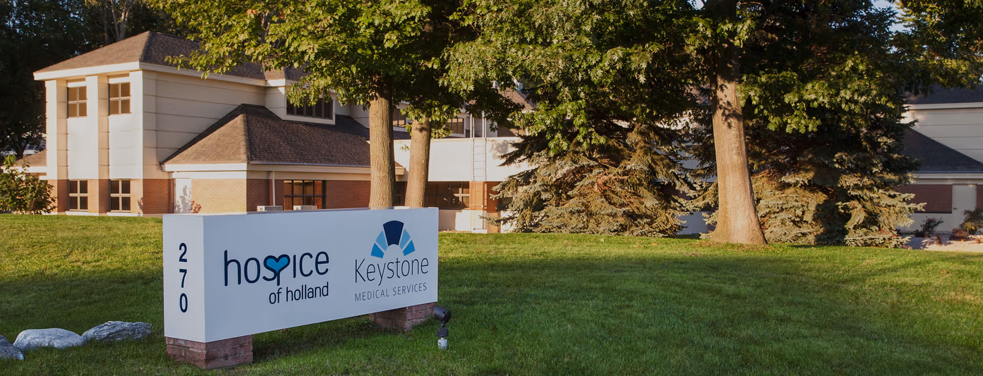 Exterior view of Hospice of Holland building with a large sign on the lawn.