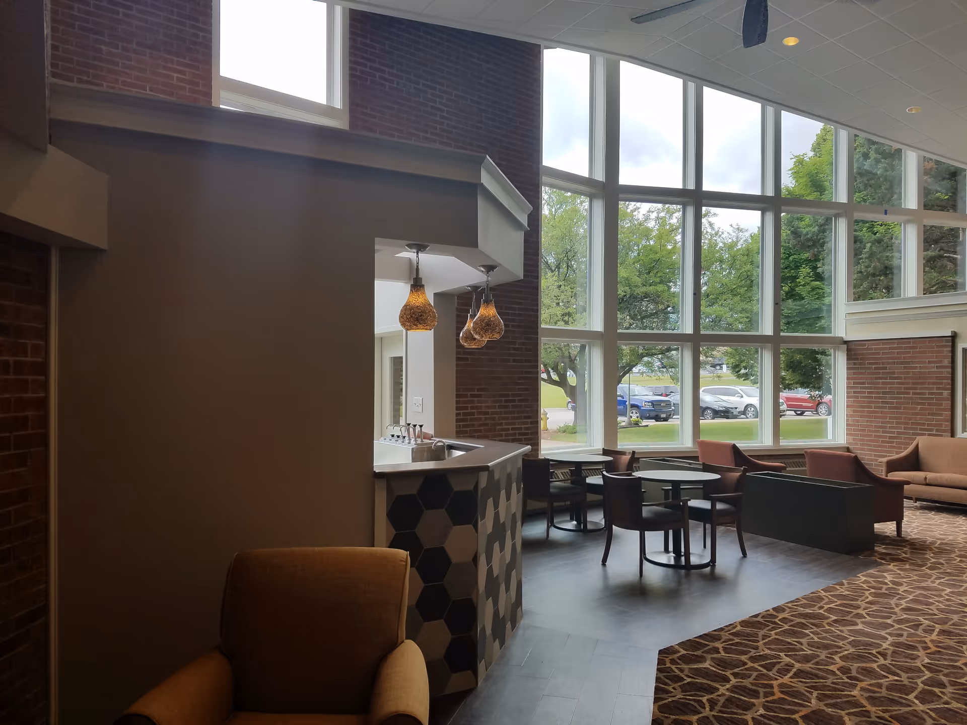 Bright lounge area with large windows, a hexagon-tiled counter, and grouped seating.