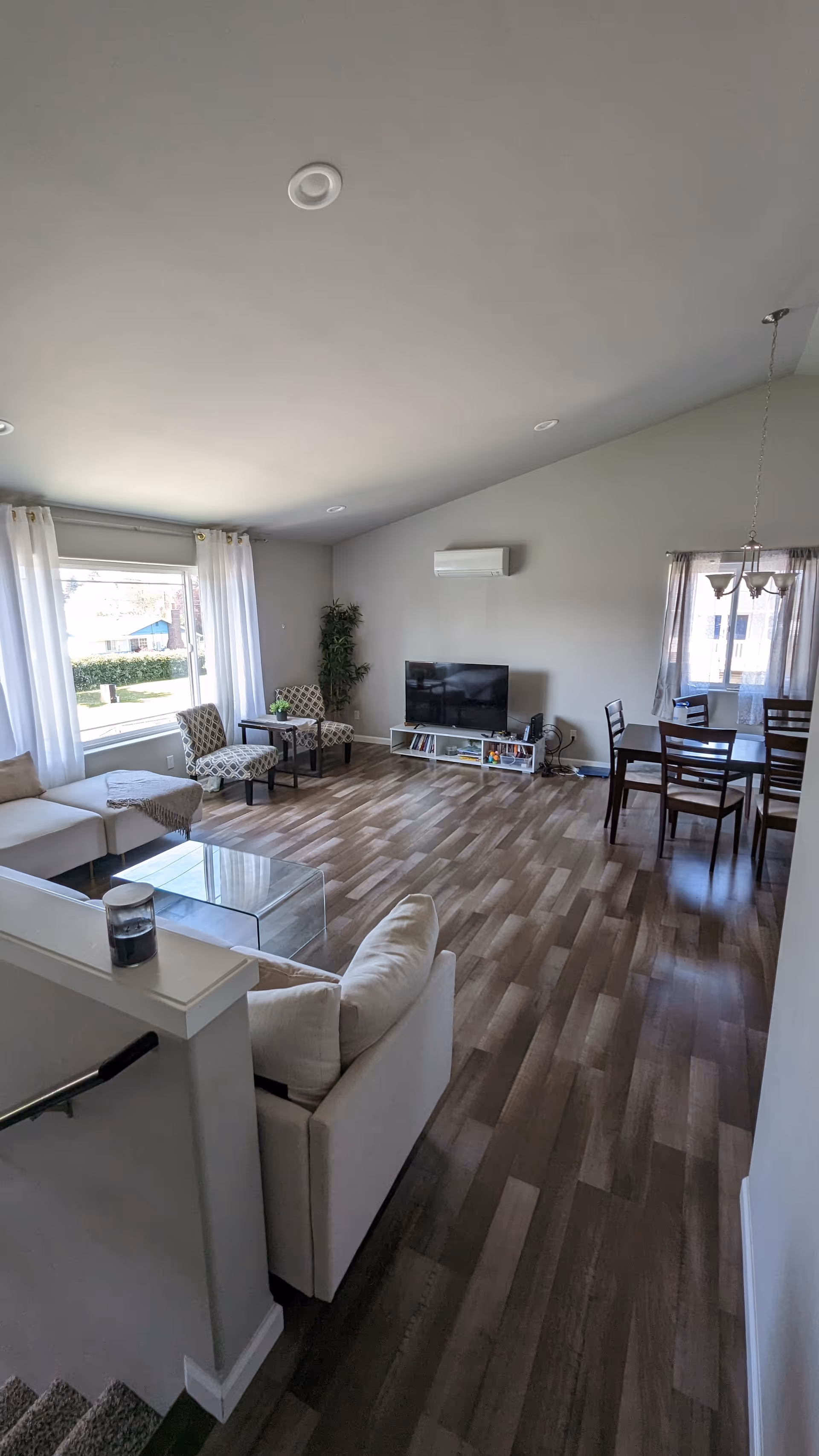 Living room in Nalka Adult Family Home with sofa, TV, dining table, and windows.