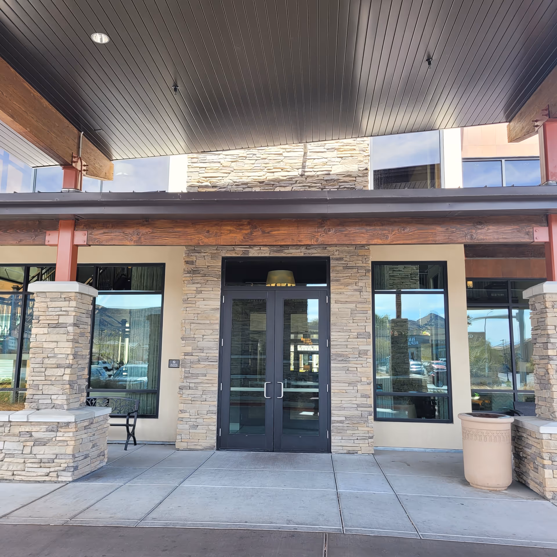 Exterior view of a senior living facility entrance with stone walls and glass doors.