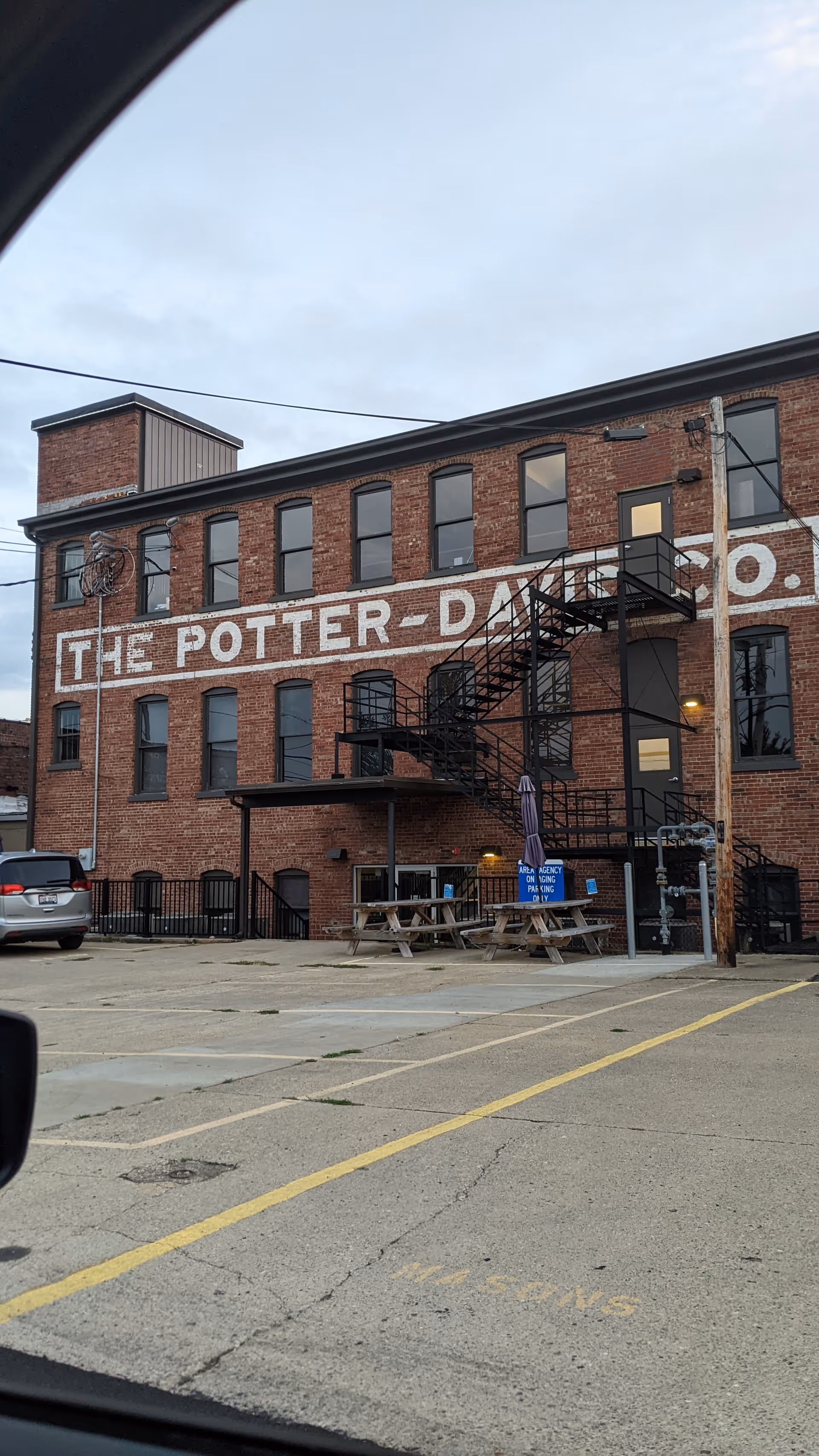 Brick building front with large white lettering, exterior stairs, and a small outdoor seating area.