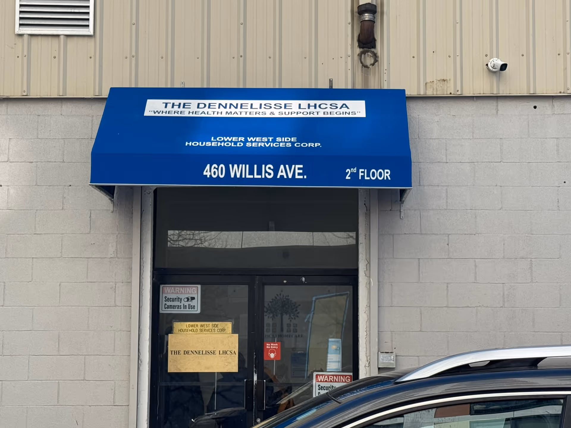 Blue awning over a storefront doorway reading Lower West Side Household Services Corp, 460 Willis Ave.