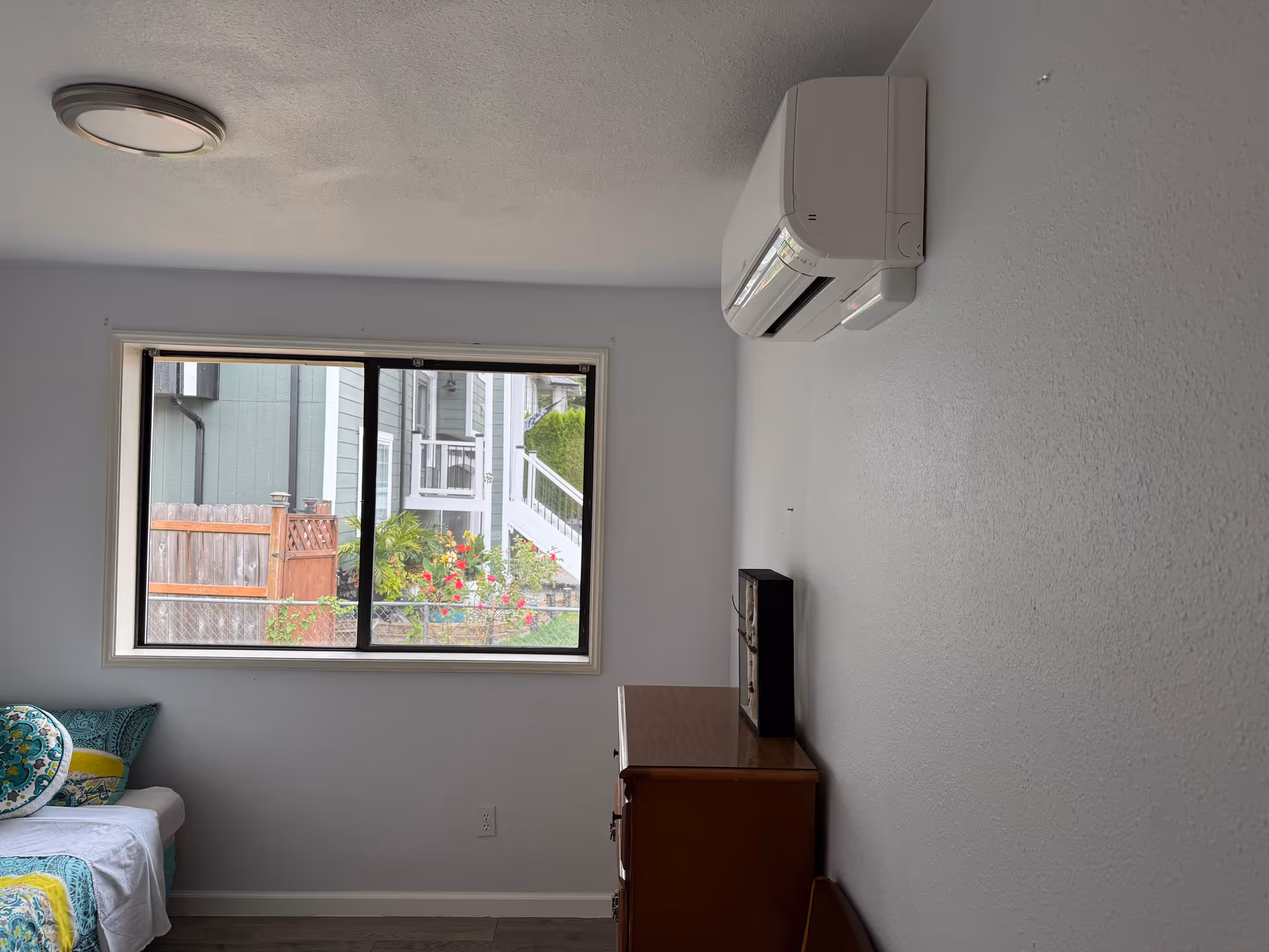 Small bedroom with a window, bed, dresser, and wall-mounted air conditioner.