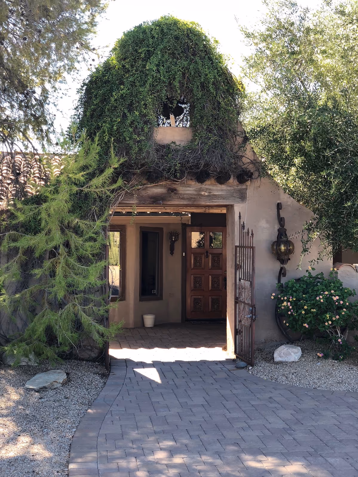 Rustic building entrance with a wooden door, archway, and surrounding greenery