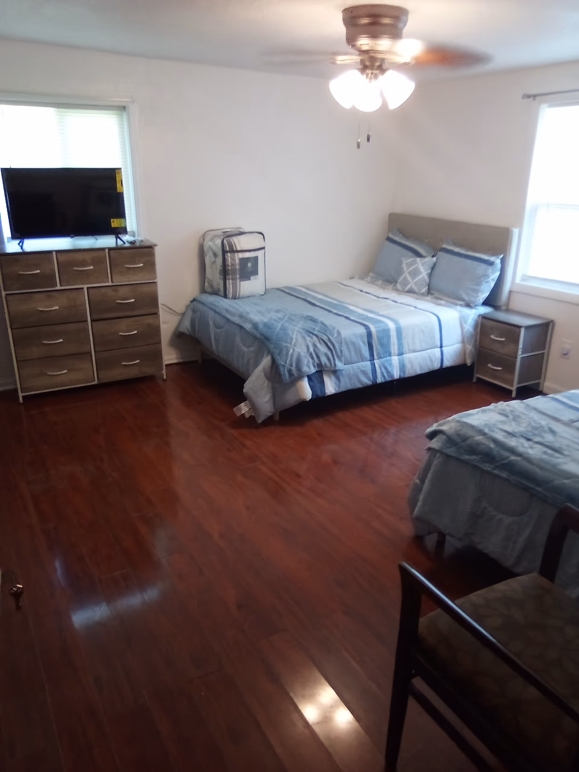View of a shared bedroom with two beds, dresser, and TV.