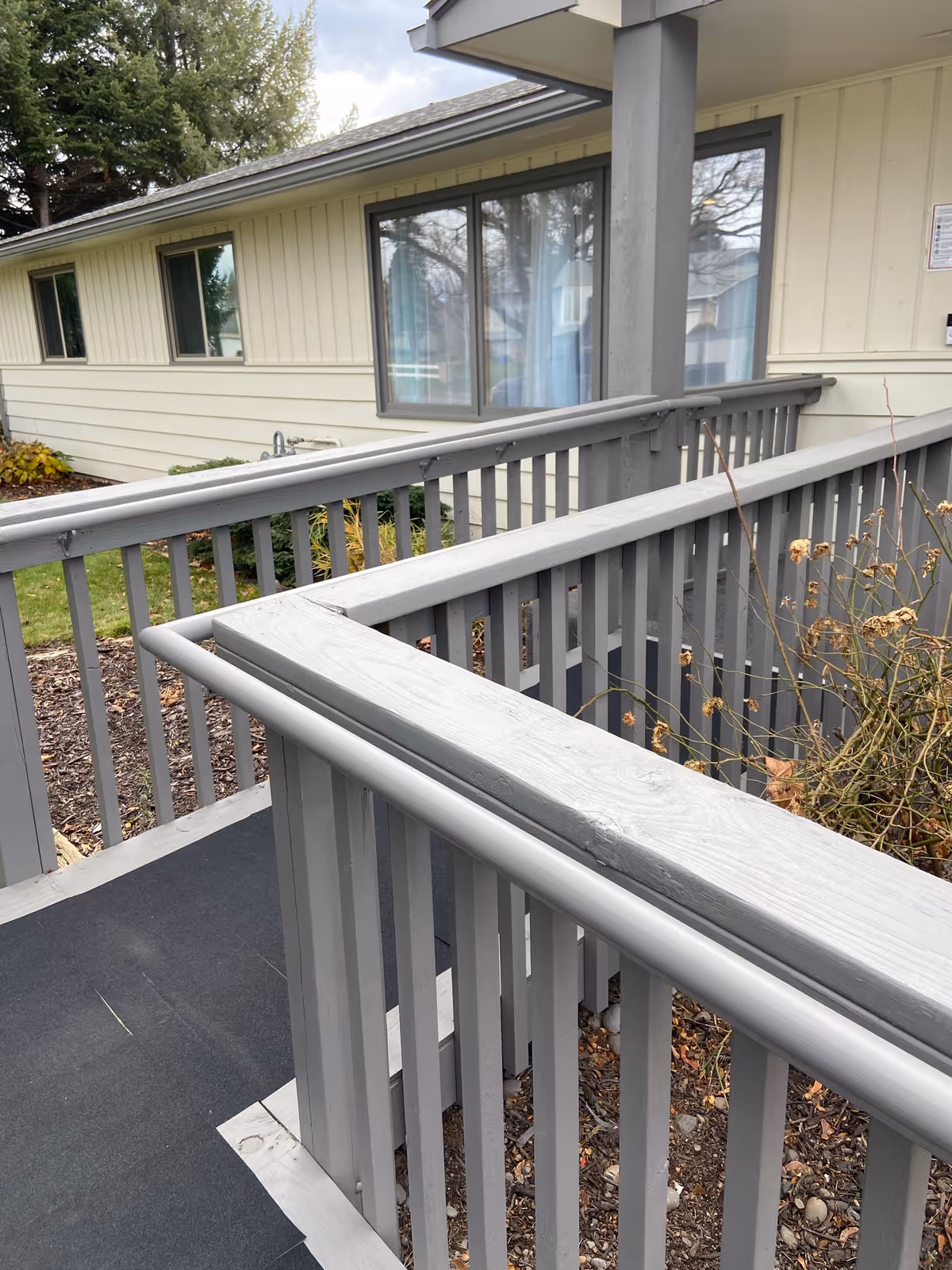 Outdoor wooden deck railing alongside a beige senior living facility exterior.
