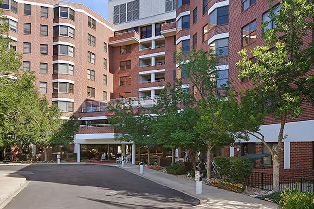 Exterior view of a brick senior living building with trees and an entrance canopy.