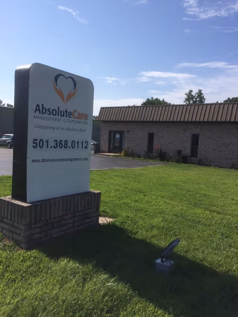 Front exterior of Absolute Care Management Corporation building with a large sign on a grassy lawn.