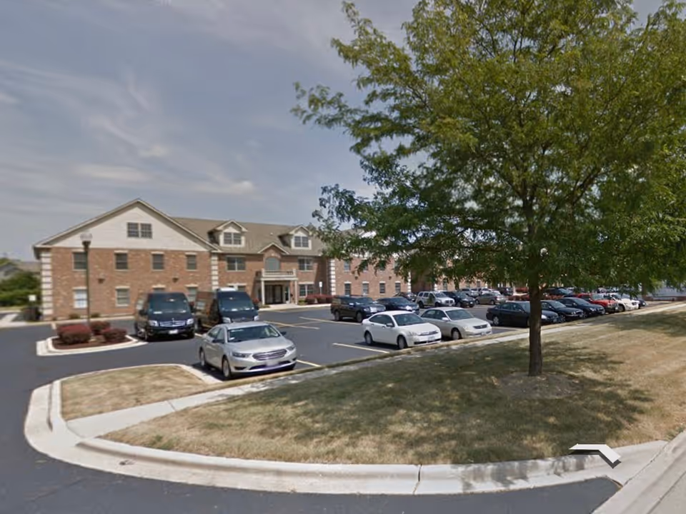 Front view of a brick senior living facility with a parking lot