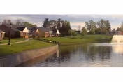 Outdoor lawn area with a water fountain and cottages along a lake at Menno Haven.