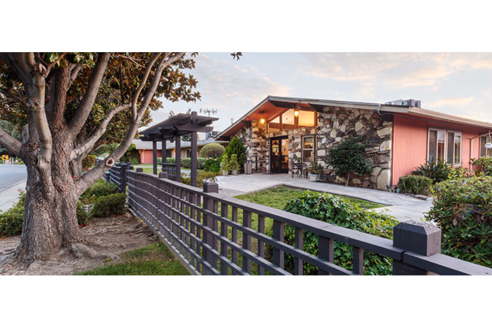 Sunnyvale Post-Acute Center exterior with stone facade, red siding, and a fenced walkway.