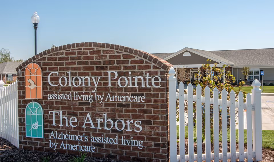 Brick sign displaying Colony Pointe and The Arbors with a white picket fence.