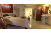 A Seaside Health bedroom with two beds, nightstand, curtain, and a pedestal sink.