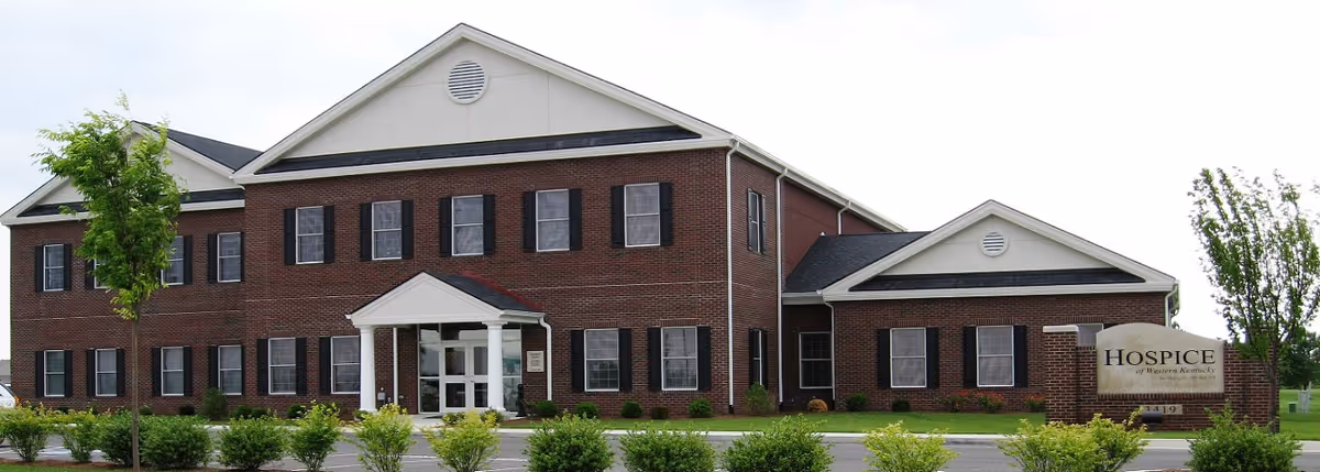 Brick hospice building with white entrance, black shutters, and a Hospice sign.