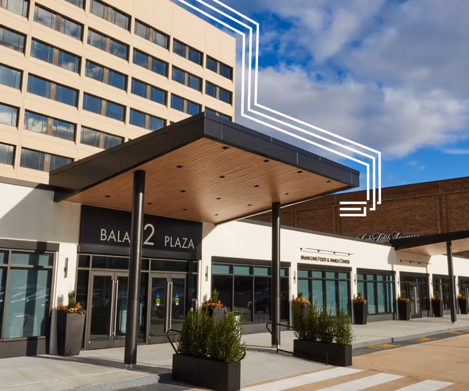 Modern multi-storefront building exterior with glass doors and planters.