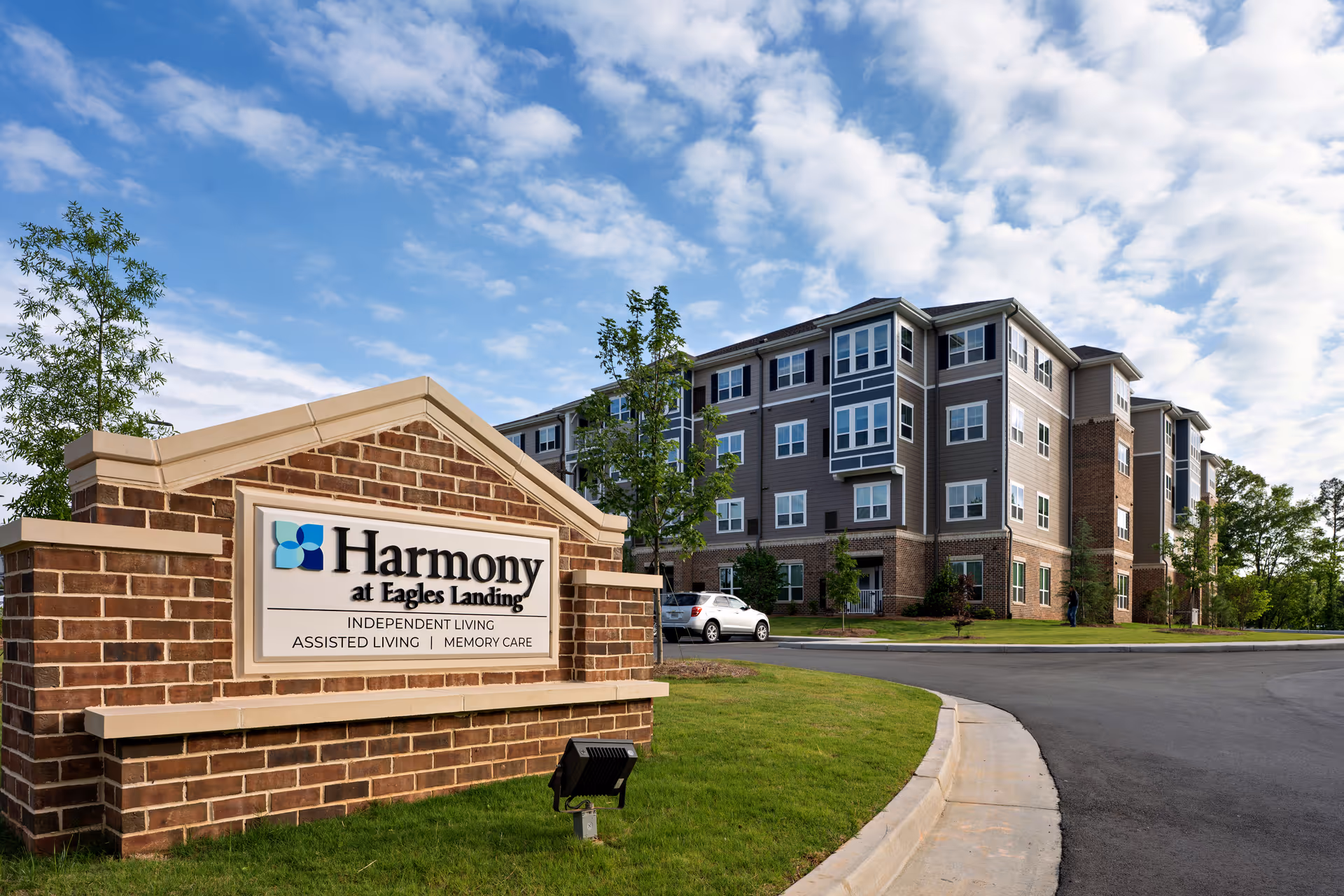Harmony at Eagles Landing sign in foreground with a multi-story building behind