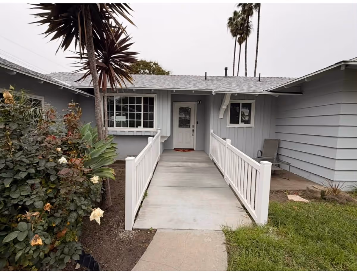 Front entrance of a gray, single-story building with a wheelchair ramp.