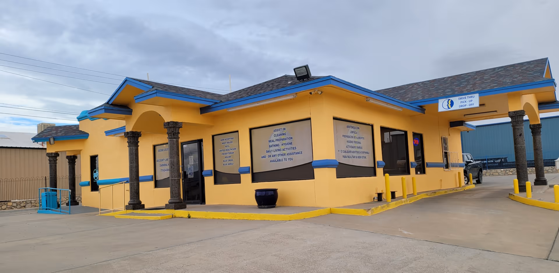 Yellow and blue single-story facility exterior with columns and a drive-thru entrance.