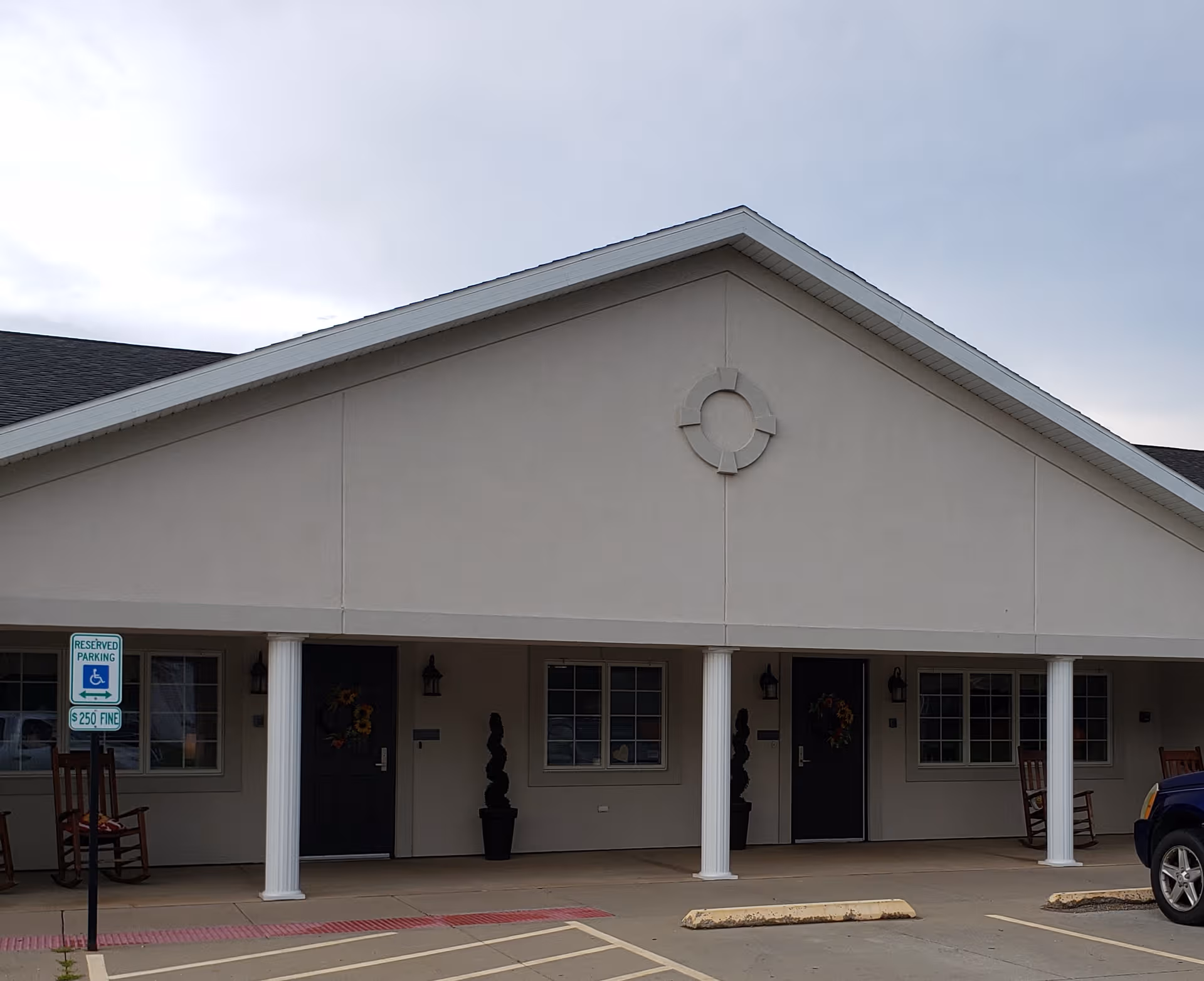 Front view of StoneBridge Memory Care building entrance with columns, doors, and a parking lot.