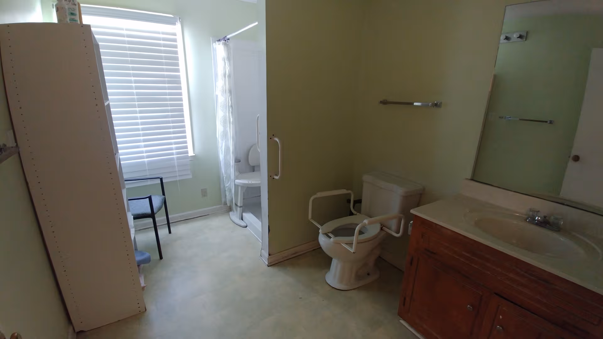 Accessible bathroom in a senior living facility with toilet, grab bars, sink, and shower.