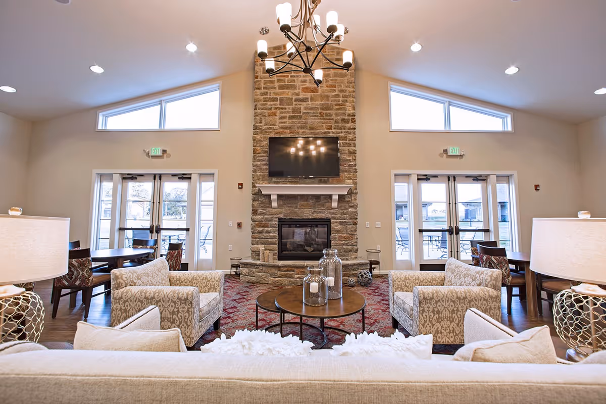Bright living room lounge with stone fireplace, sofas, tables, and glass doors.