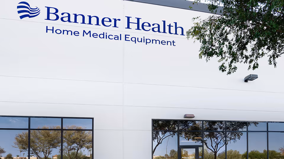 White commercial building with Banner Health Home Medical Equipment sign and trees.