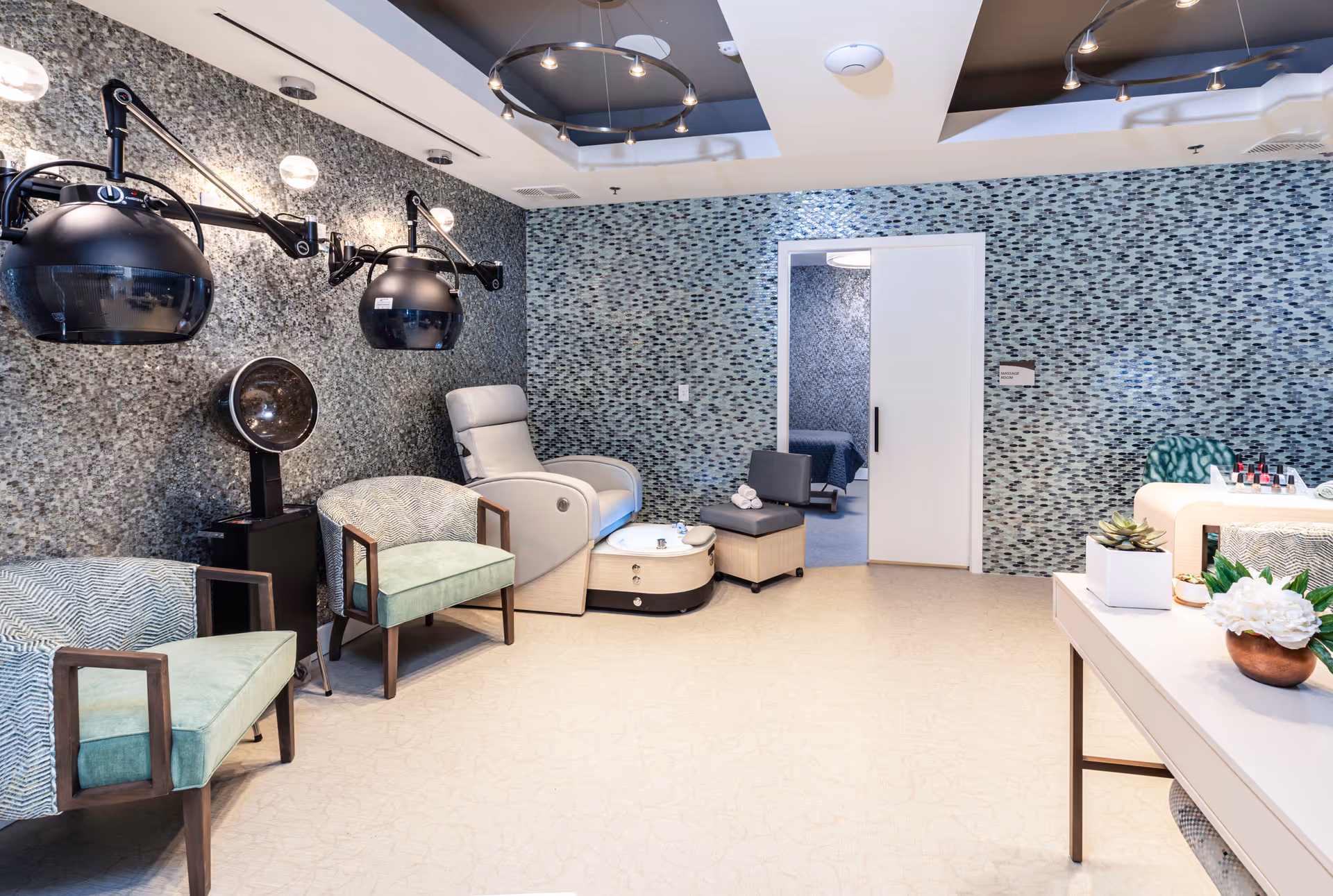 Indoor senior living salon with mosaic walls, reclining chairs, and hair styling equipment.
