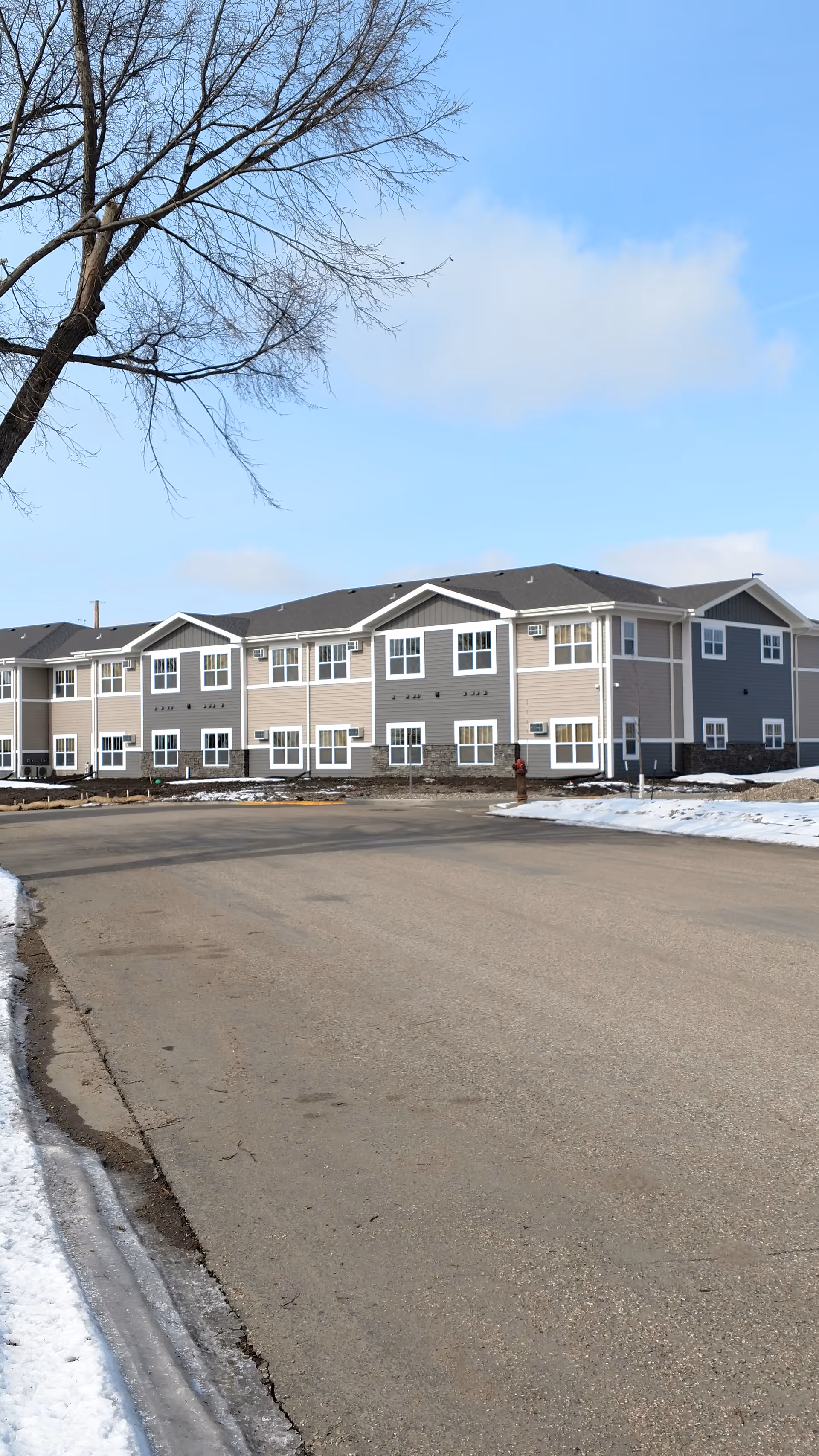 Exterior view of a multi-unit senior living facility along a snowy street.