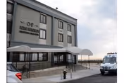 Exterior view of Beacon Rehabilitation Nursing Center with entrance canopy and parked vehicles.