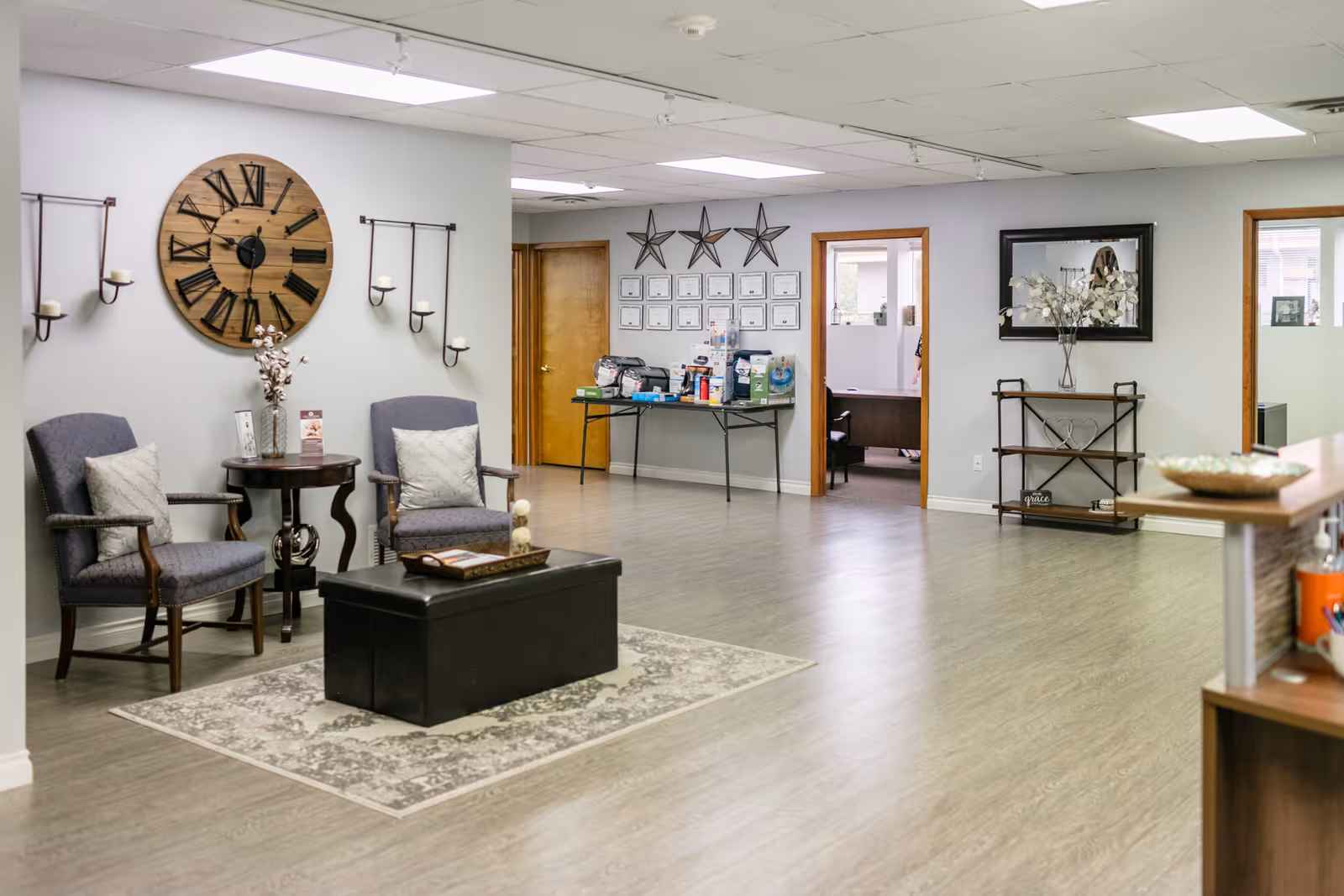 Cozy lobby area with seating, a wall clock, and hallway in a senior care facility.