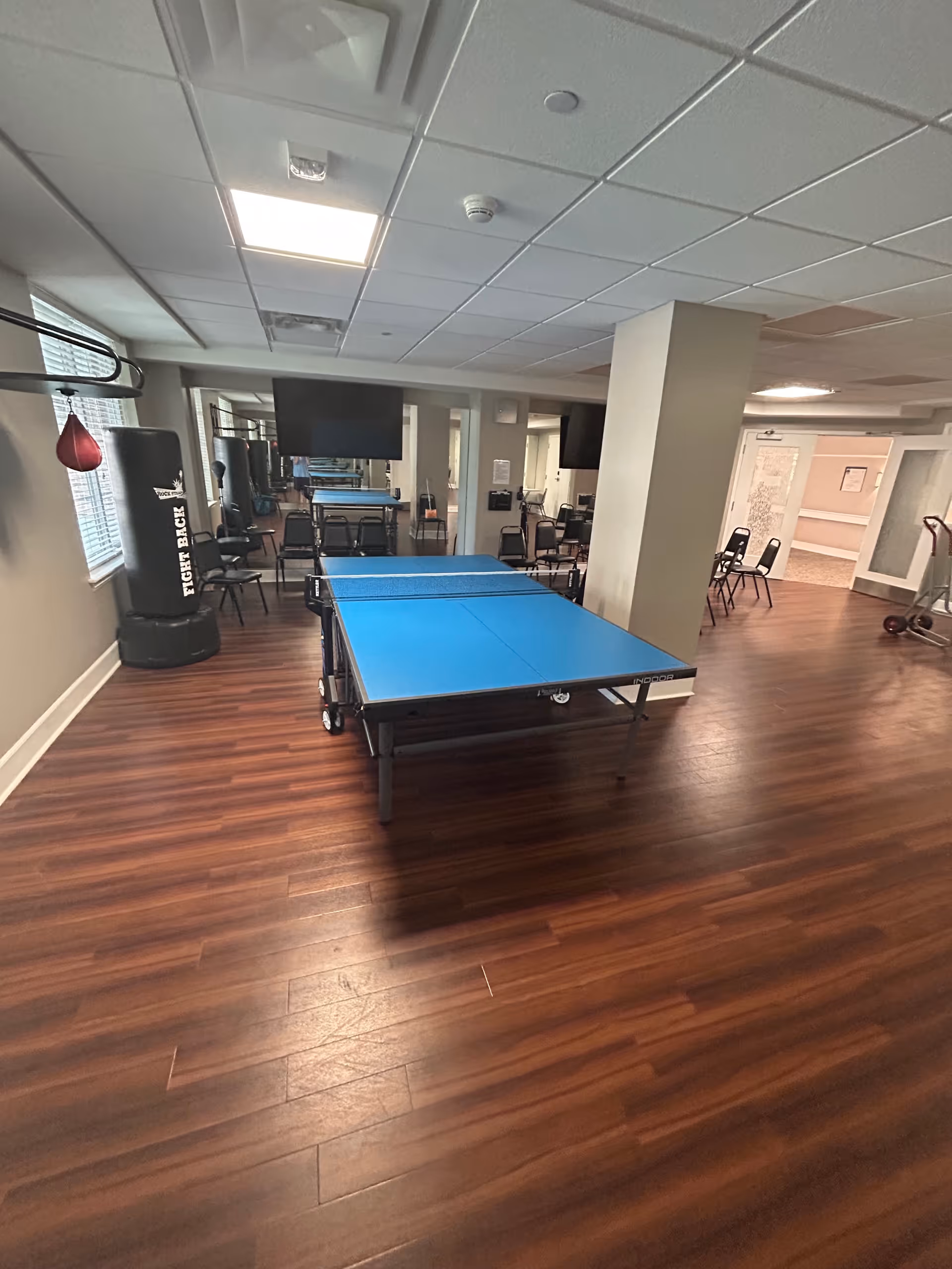 Indoor recreation room with a blue table tennis table and chairs.