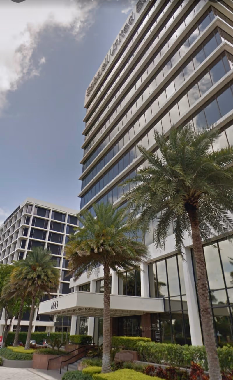 Modern multi-story senior living building with palm trees and glass facade.