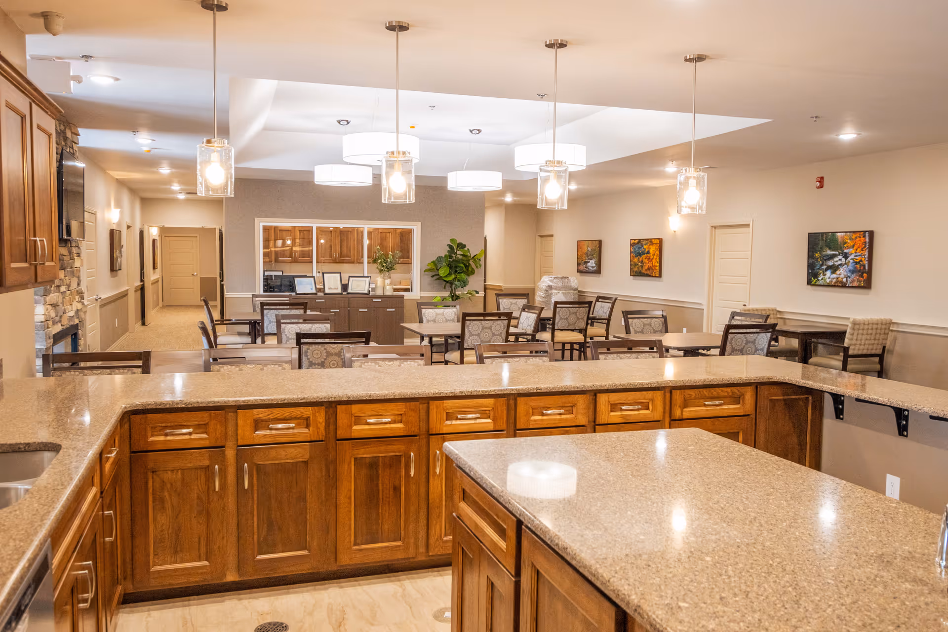 Open dining area with tables, chairs, and a granite kitchen counter.