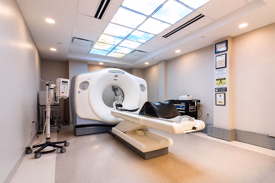 A large CT scanner with patient table in a modern radiology examination room.