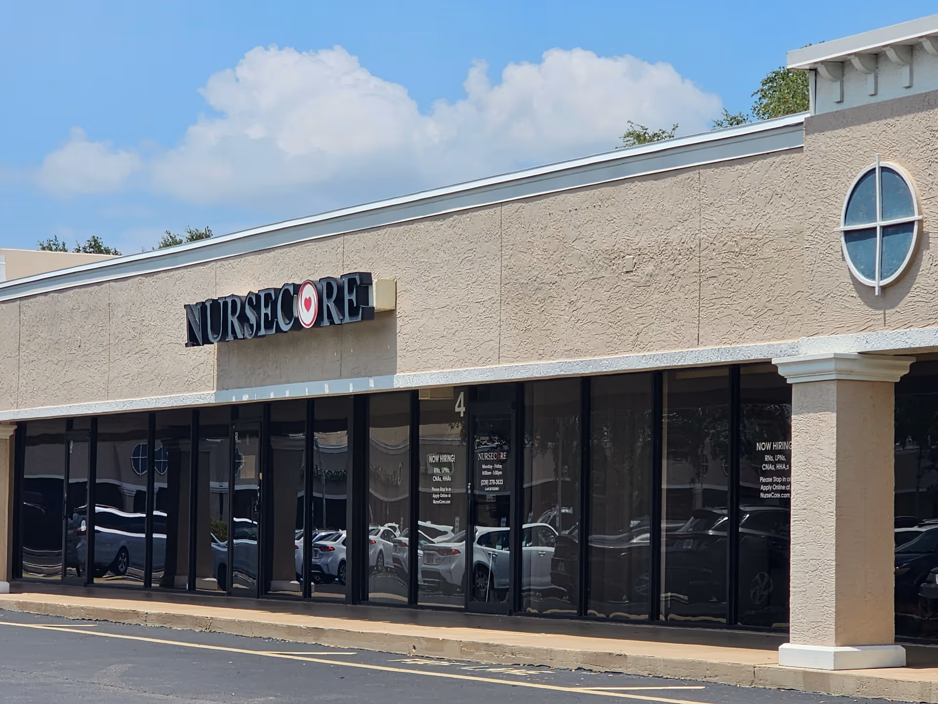 Exterior front of NurseCore building with large glass windows and parked cars.