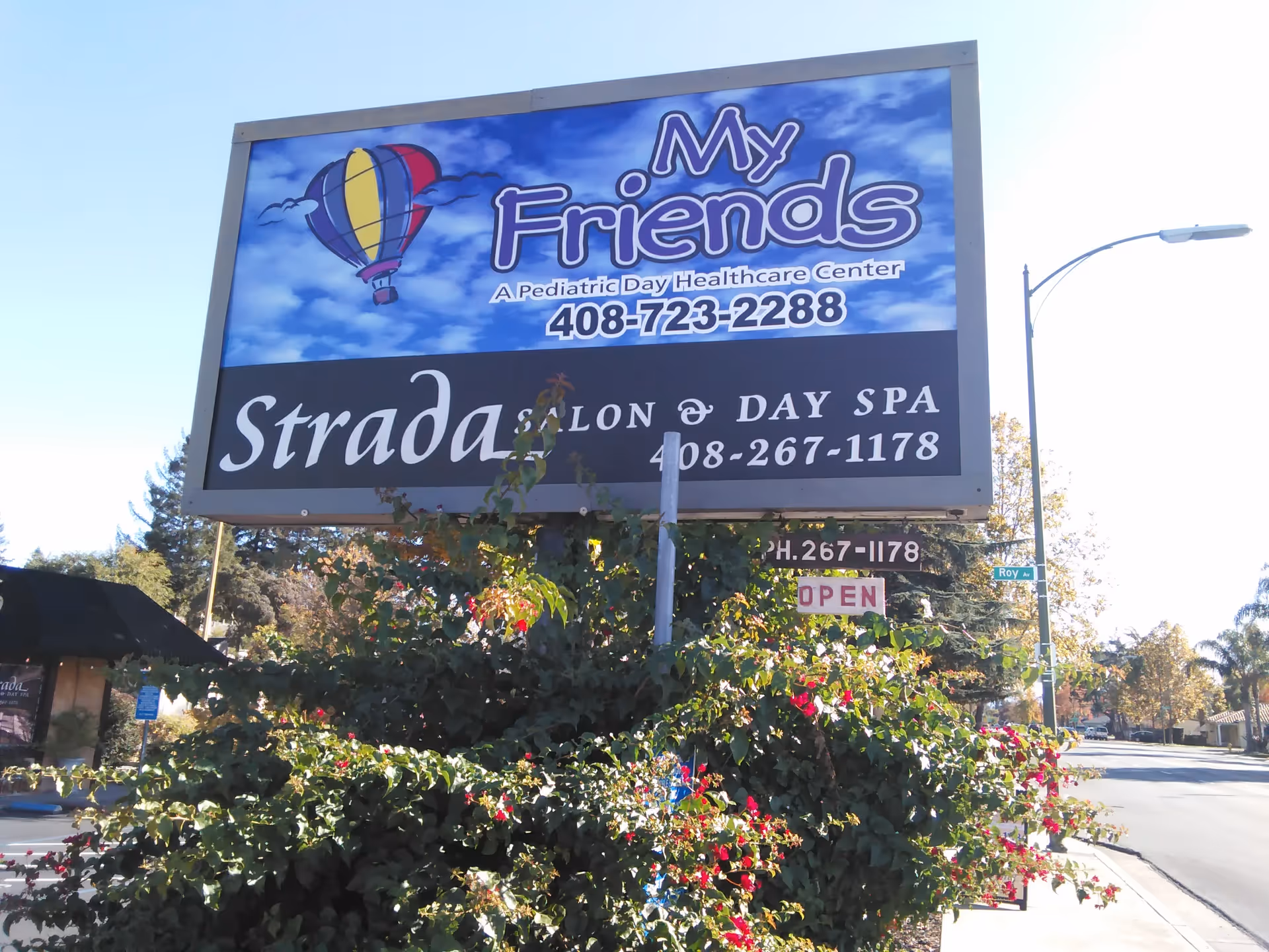 Large roadside sign advertising 'My Friends' pediatric center against a blue sky.