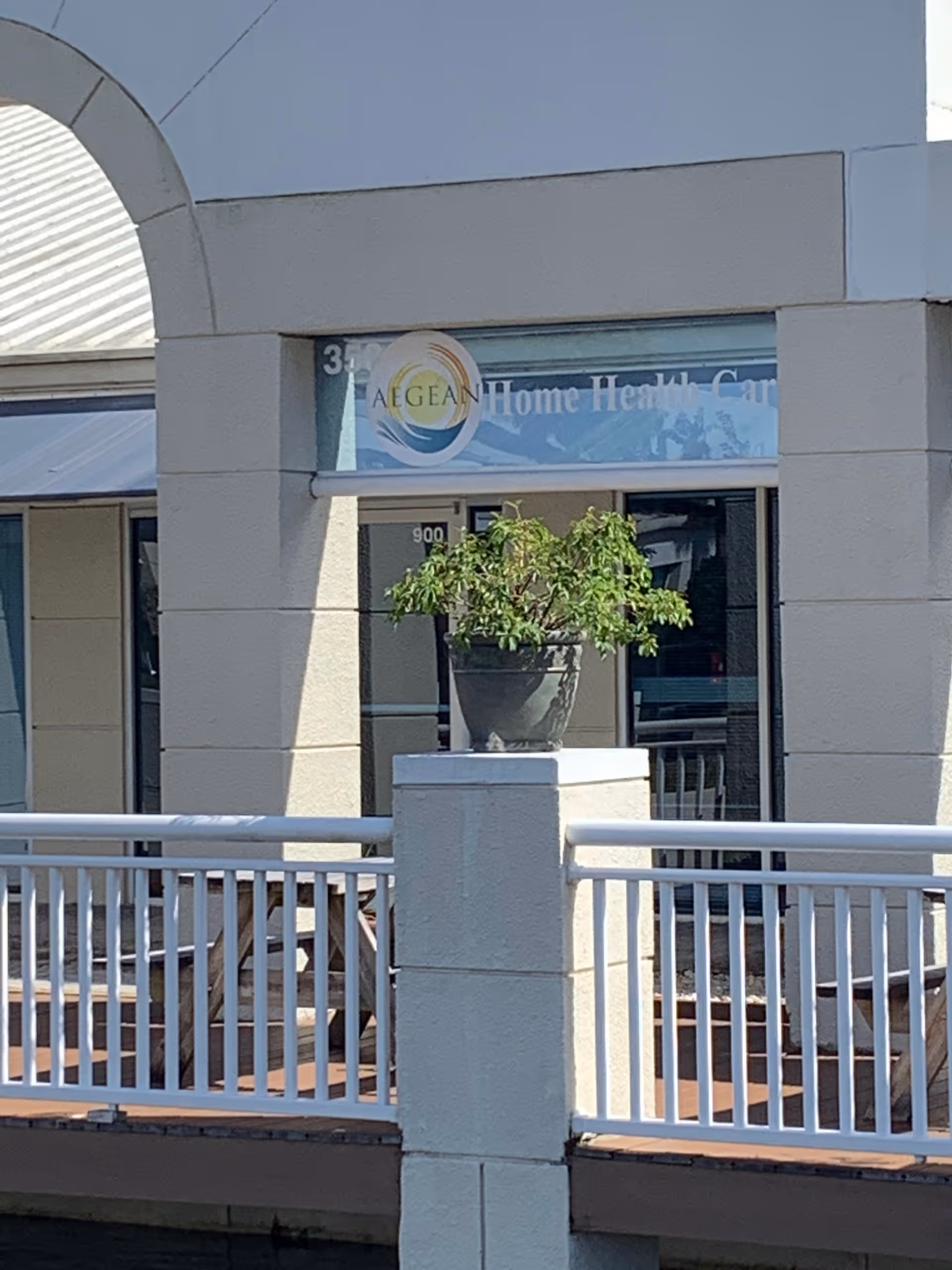 Exterior view of Aegean Home Health Care entrance with railing and potted tree.