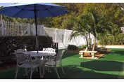 Outdoor courtyard with a round metal table, chairs, and a blue umbrella.