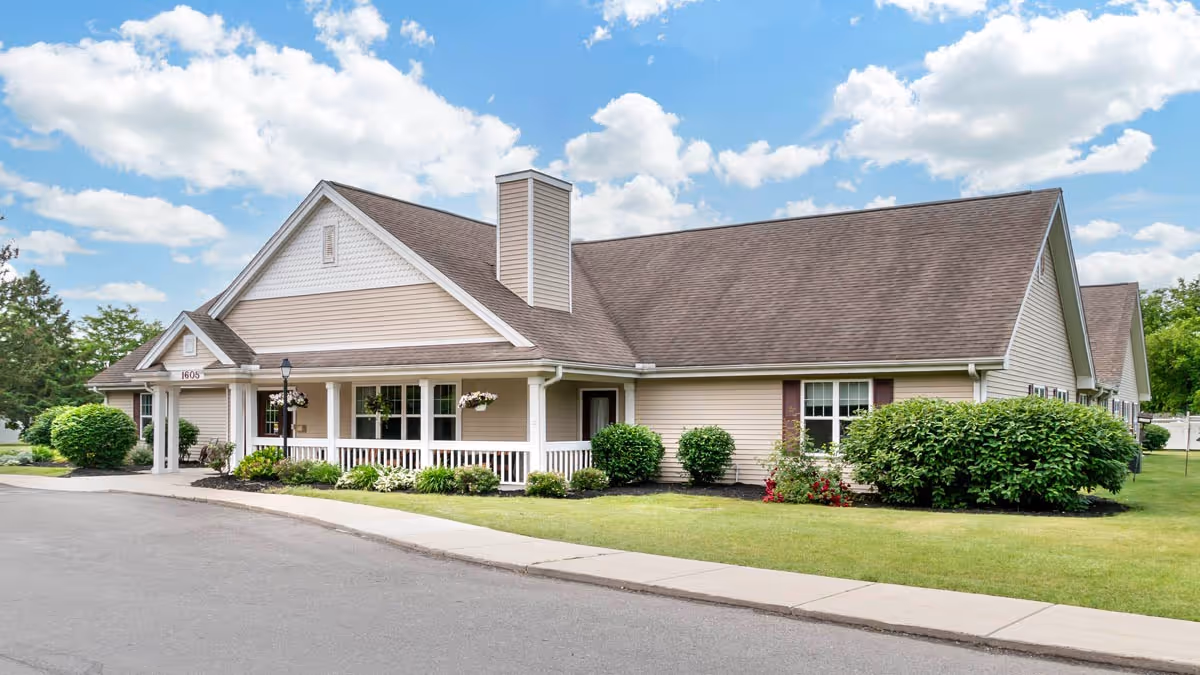 Single-story beige senior living facility with a covered front porch and manicured landscaping.