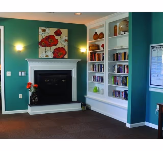 Bright living area with a white fireplace, teal walls, and built-in bookshelves.