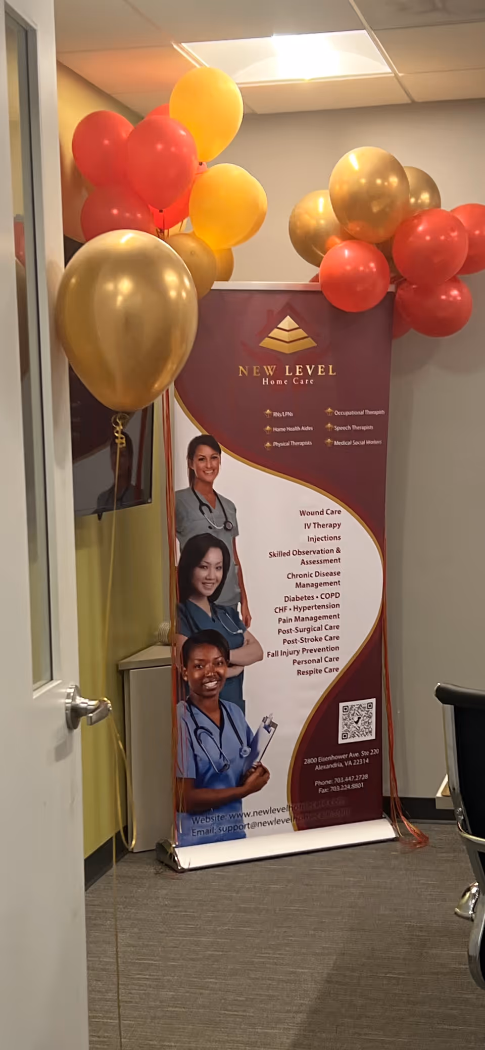 Interior hallway with a New Level Home Care banner and red and gold balloons.