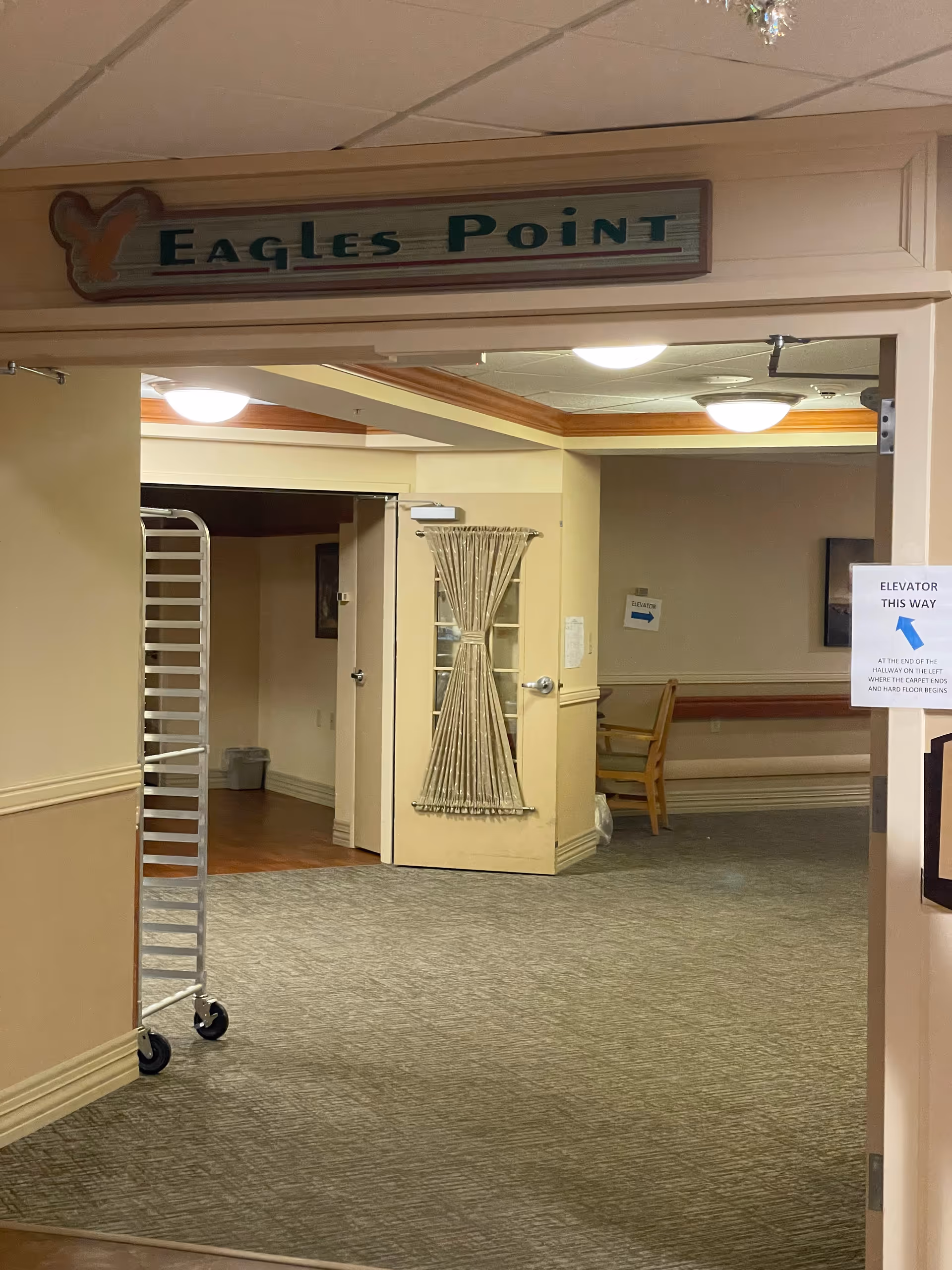 Interior hallway of Oak Hills Living Center with a cart and Eagles Point sign.