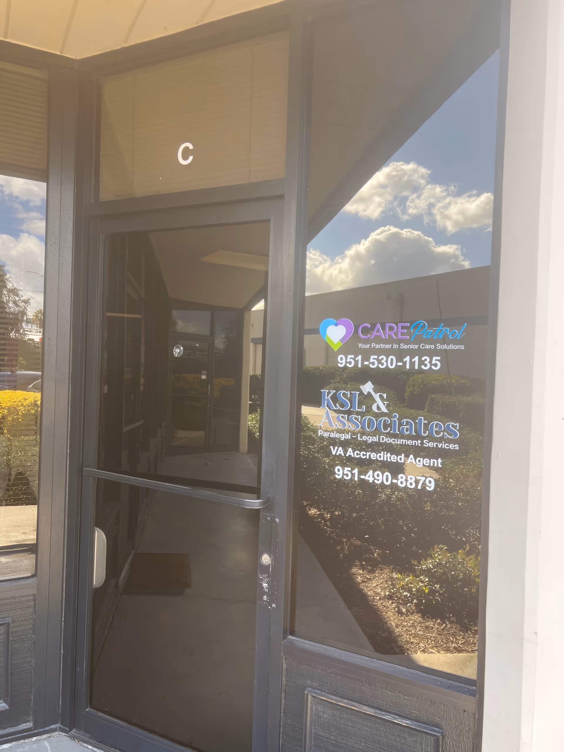 Glass entrance door with CarePatrol signage and contact numbers, front of a building.